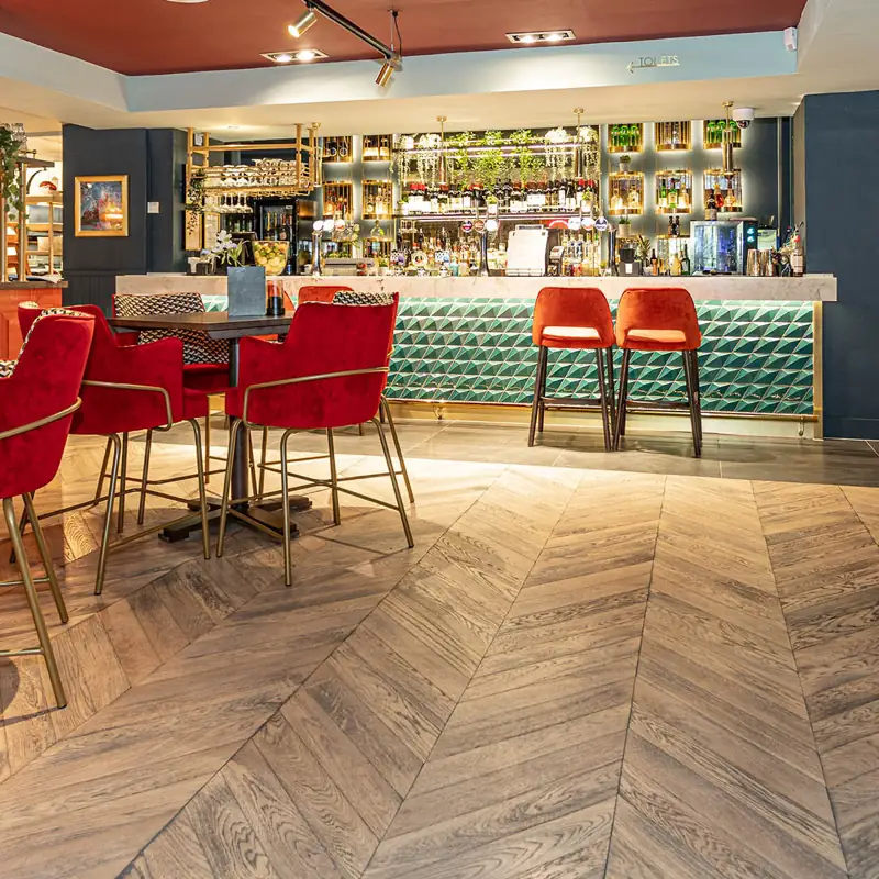Grey chevron wood flooring in a luxury bar area.