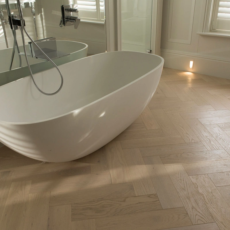 Pale oak herringbone parquet in a white bathroom.
